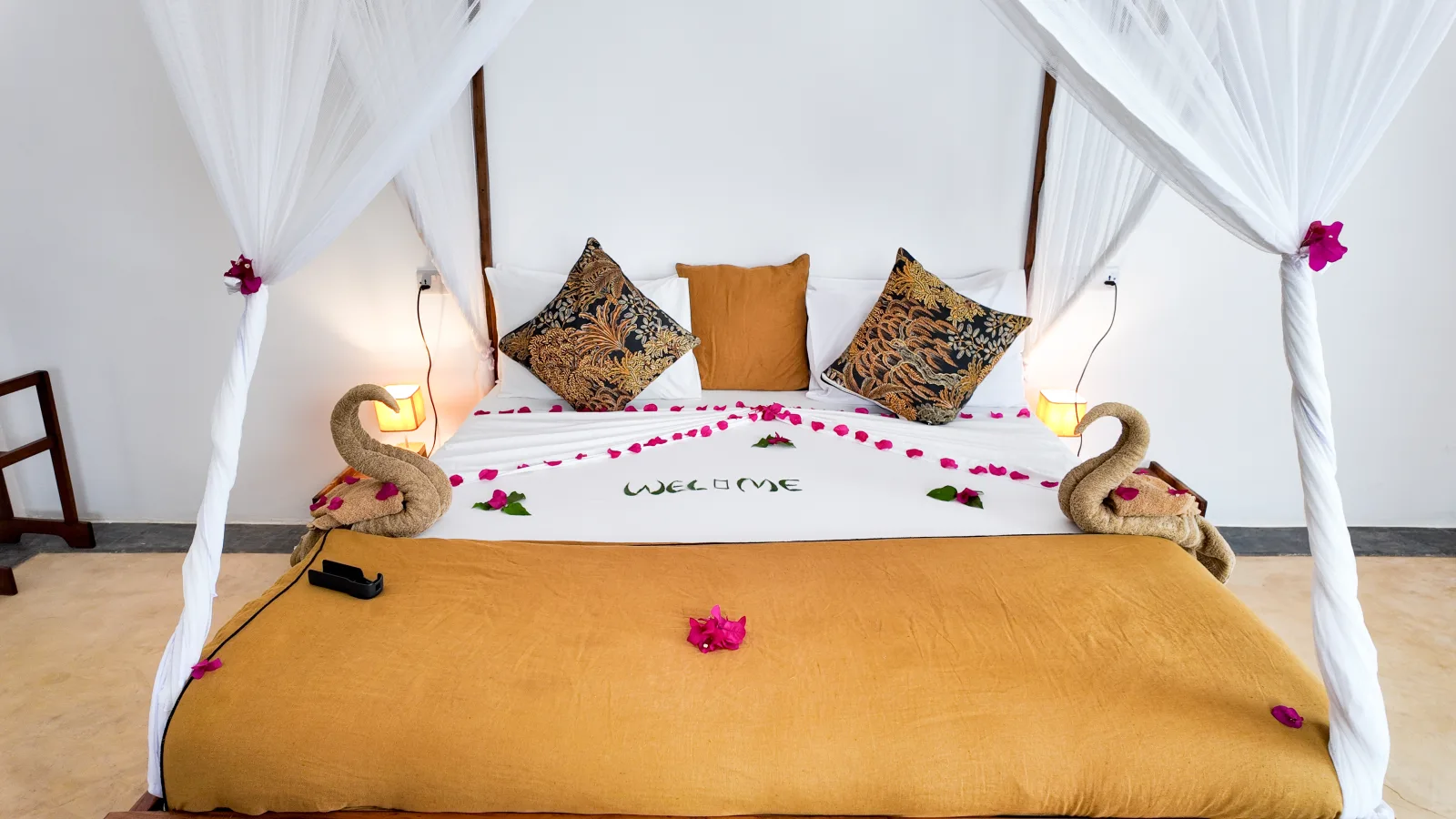 Khole Villa canopy bed prepared with flowers, warm textiles, and folded towel swans