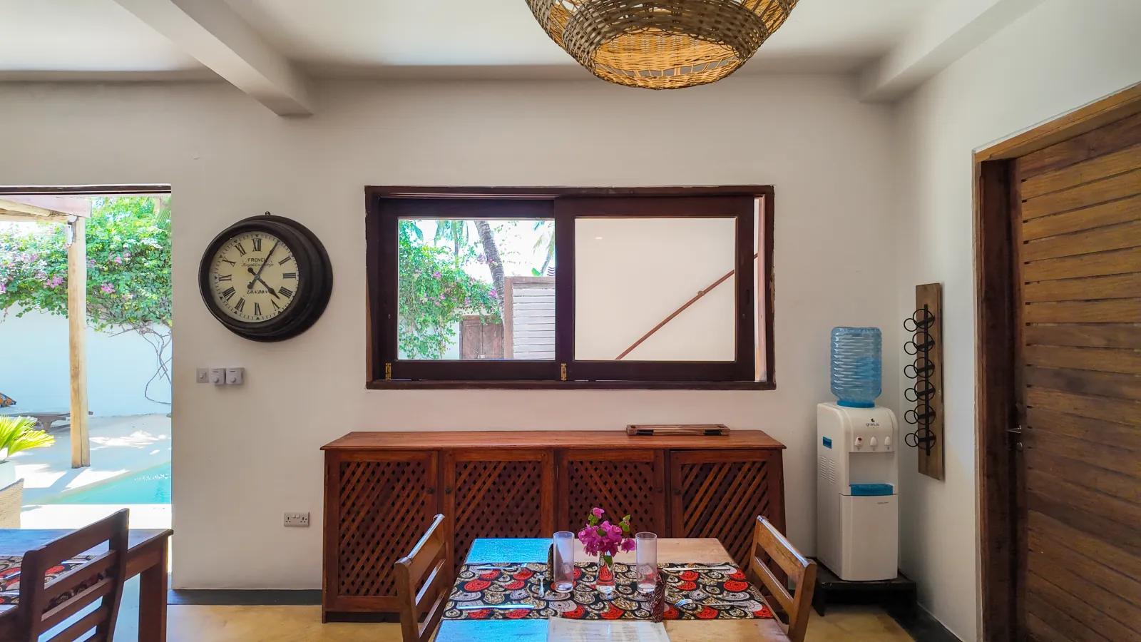 Khole Villa dining table beneath a woven light with an open view toward the pool
