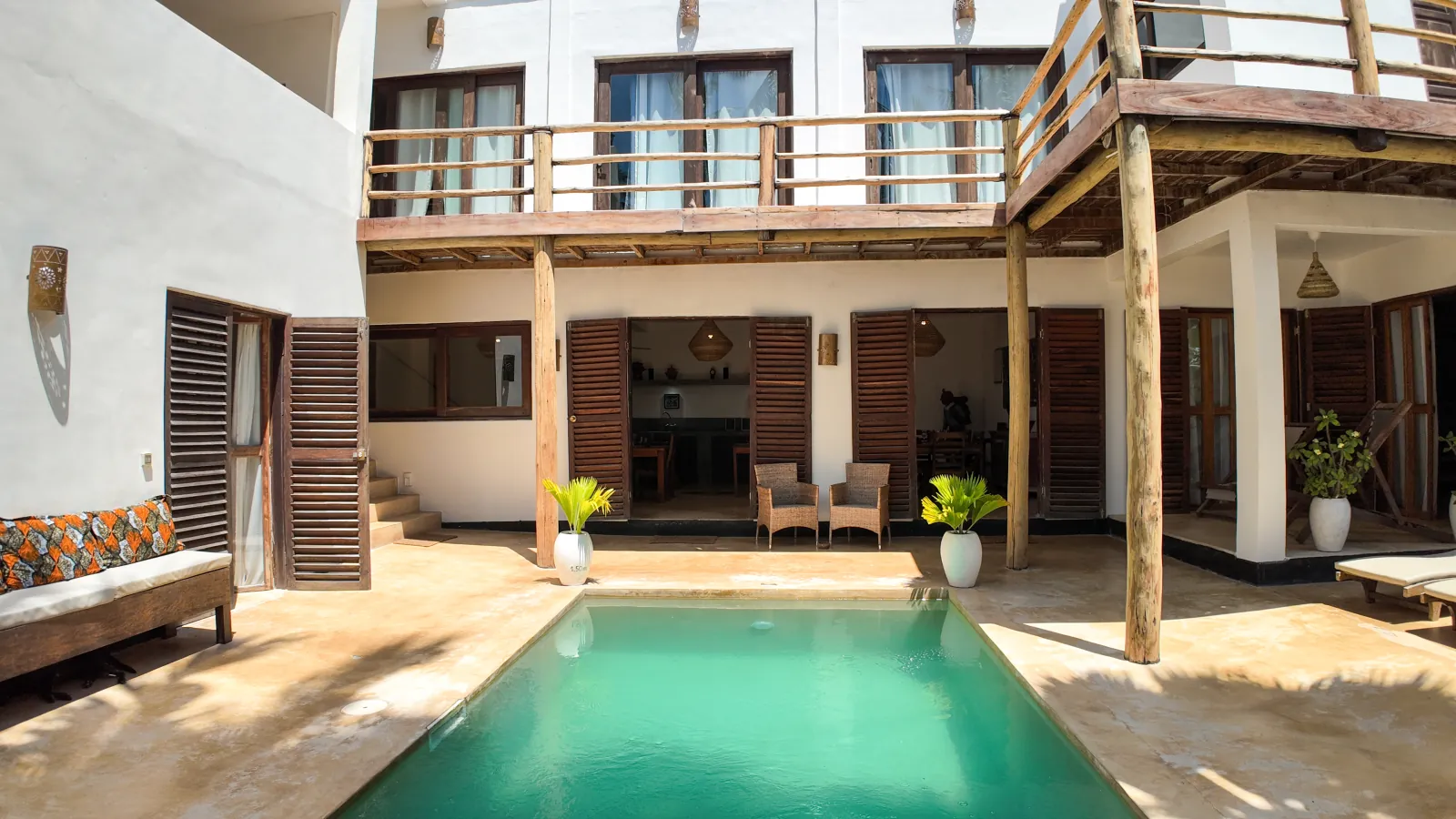 Khole Villa turquoise pool facing a wooden balcony and open shutters