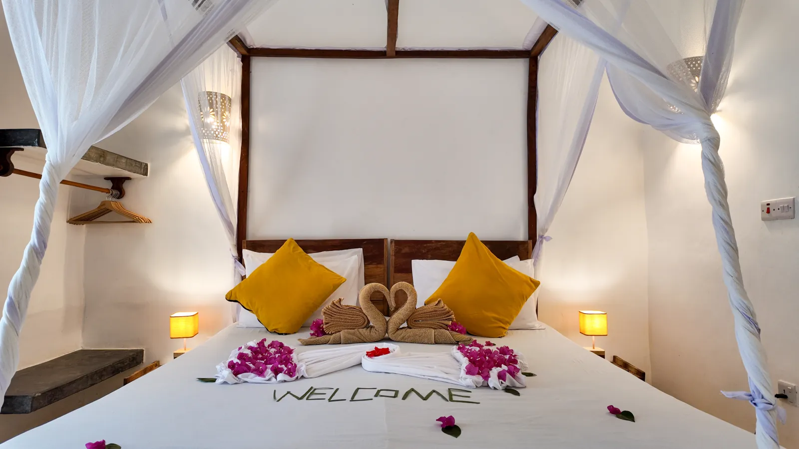 Khole Villa canopy bed with yellow cushions, towel swans, and flowers